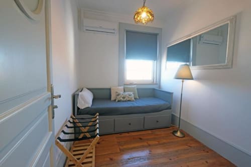 Quarto compacto no Santiago de Caminha Boutique Hostel com cama diurna, piso de madeira nobre, espelho e vista para o jardim em Caminha