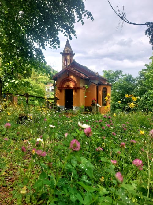 Charmante chapelle jaune entourée de fleurs sauvages au Palazzo Losio à Ponzone, Italie
