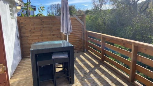 Terrasse en bois avec salon de jardin noir et parasol à la Résidence KaZa Lou-Lou en Guadeloupe, vue sur mer