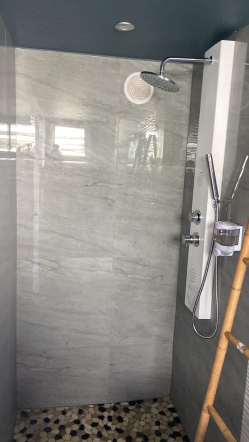 Salle de bain moderne aux carrelages effet marbre et pomme de douche pluie à l'appartement KaZa Bel'Vi à Capesterre de