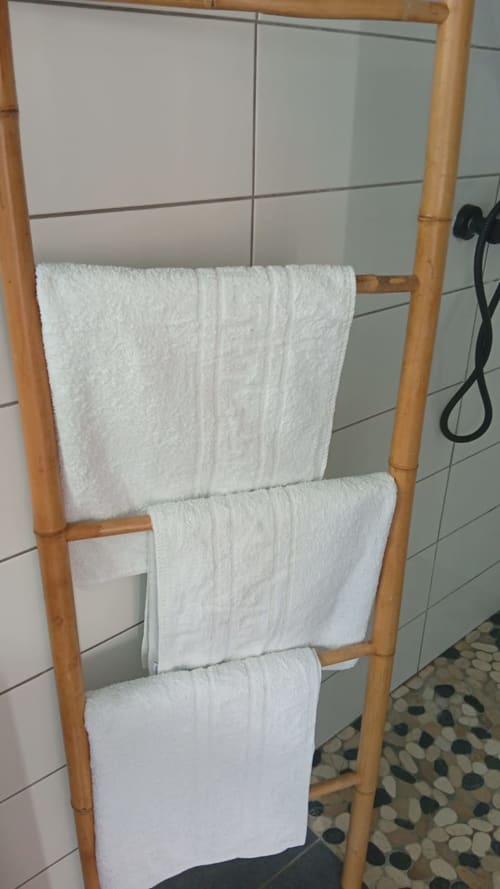 Porte-serviettes en bambou avec serviettes blanches roulées dans la salle de bain de la résidence KaZa Lou-Lou, Guadeloupe