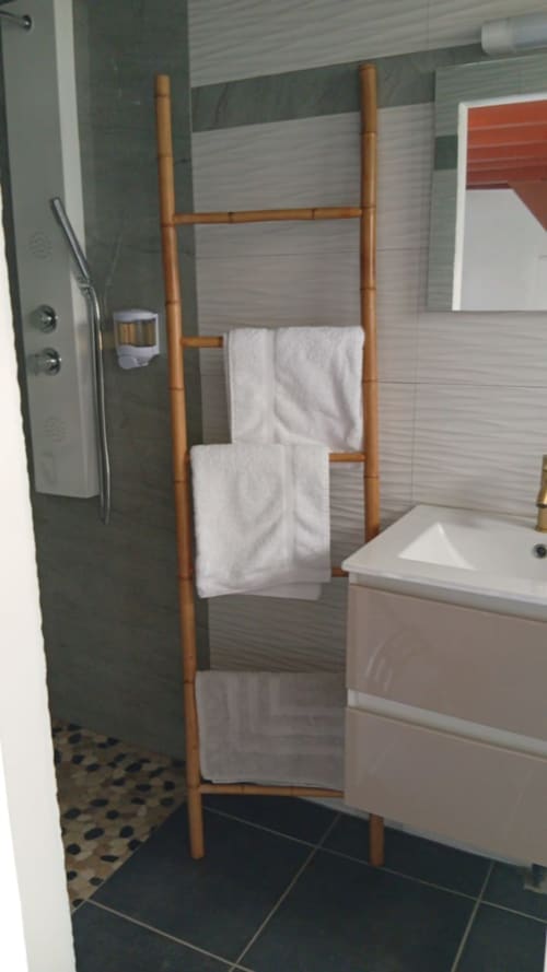 Salle de bain moderne à la Résidence KaZa Lou-Lou avec échelle à serviettes en bambou, lavabo blanc et carrelage rayé