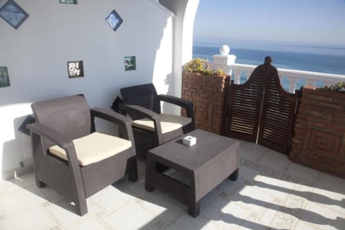 Terraza soleada de Hostal Mar de Frente con asientos de mimbre con vistas al mar Mediterráneo en Los Caños de Meca