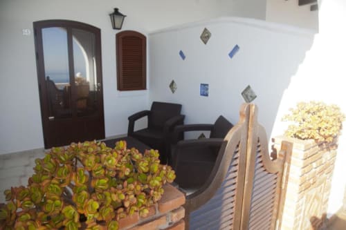 Zona de estar en la terraza del Hostal Mar de Frente en Los Caños de Meca con sillas negras, plantas en macetas y vistas al mar