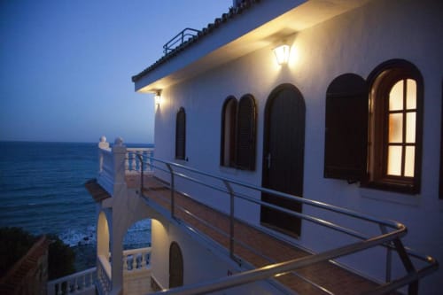 Terraza frente al mar del Hostal Mar de Frente al atardecer, Los Caños de Meca, edificio blanco iluminado con vistas al Mediterráneo