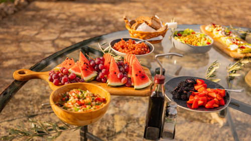Festin en plein air à Agroturismo Ses Illes : pastèque, raisin, salades fraîches, maïs, baies et spécialités locales sur table rustique