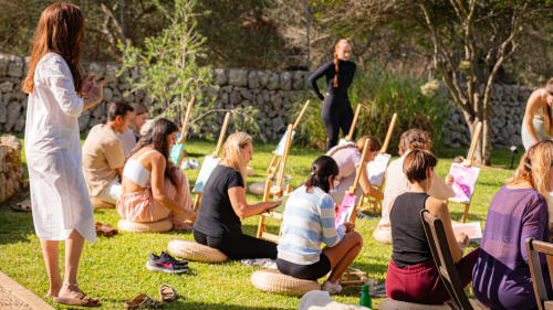 Atelier d'art en plein air à l'Agroturismo Ses Illes à Costitx, des visiteurs peignant sur des chevalets dans un cadre de jardin