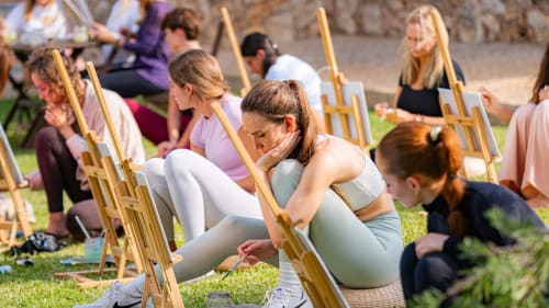 Des invités peignent en plein air à l'Agroturismo Ses Illes à Costitx lors d'une activité créative de groupe sur la pelouse.