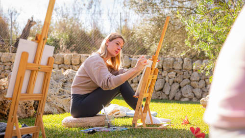 Artiste peignant en plein air à l'Agroturismo Ses Illes à Costitx, Espagne, avec murs de pierre et décor de jardin