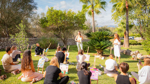 Atelier d'art en plein air à Agroturismo Ses Illes à Costitx, clients peignant dans un jardin verdoyant.