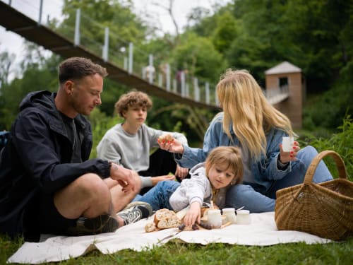 Family enjoying a picnic near Aux 4 Chalets Corbion in Bouillon with scenic bridge backdrop