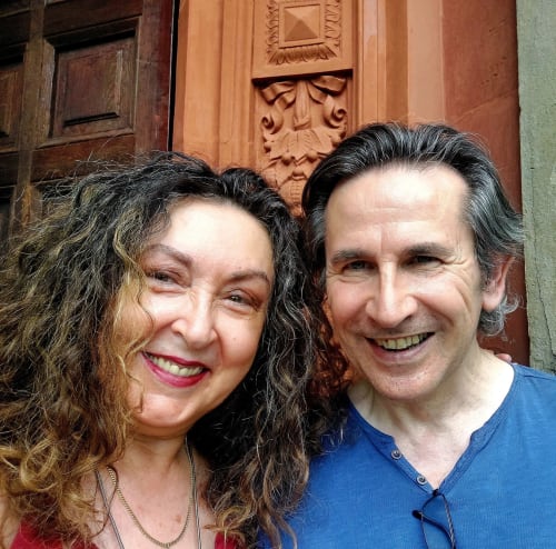 Deux membres du personnel souriants au Palazzo Losio, un hôtel historique à Ponzone, en Italie, devant des portes en bois ornées.