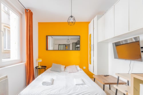 Chambre Studio 101 à Metz avec mur d'accent orange audacieux, literie blanche, TV et équipements modernes
