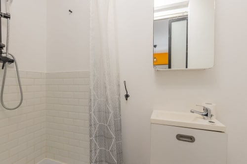Salle de bain moderne du Mattbnb Studio 101 à Metz avec carrelage blanc, douche, lavabo et miroir