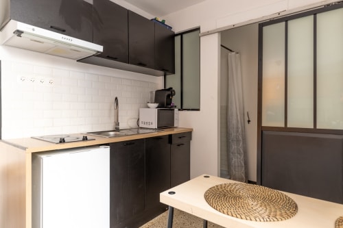 Cuisine moderne du studio Mattbnb Metz avec armoires noires, plan de travail en bois, carrelage métro blanc et coin repas