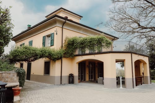 Villa Albertina a Parma: elegante villa in pietra e crema con portico ad archi, muri edera e terrazza in laterizio