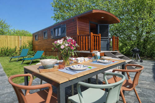 Roulotte Gîtes à Porspoder avec terrasse en bois, table de jardin, fleurs roses et chaises longues
