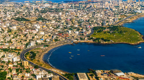 Aerial view of Dakar's coastline with blue waters, beaches, and residential buildings near DakarByDays