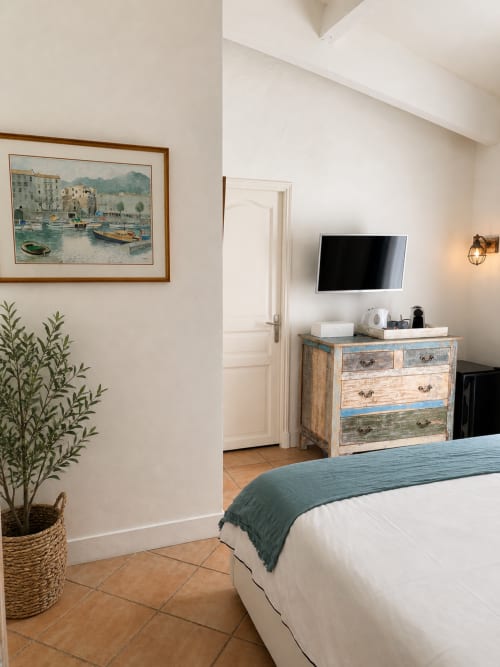 Das Schlafzimmer La Saint Raphaël in La Parenthèse de Villepey mit Küstenkunst, farbenfroher Kommode und Flachbildfernseher