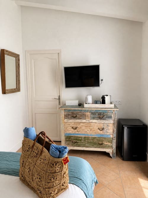 Modernes Hotelzimmer in La Parenthèse de Villepey mit rustikaler Kommode, Wandfernseher und blauen Akzenten in Saint Aygulf