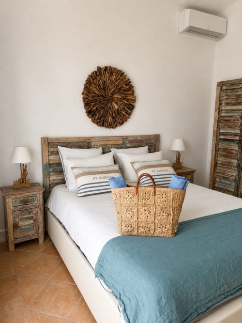 Das Schlafzimmer La Saint Raphaël in La Parenthèse de Villepey mit rustikalem Holzbett, weißer Bettwäsche und blauen Akzenten in Saint Aygulf
