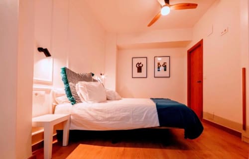 Dormitorio La Dormilona en Gestyp-AT de Mérida con cama, piso naranja, puerta roja y ventilador de techo