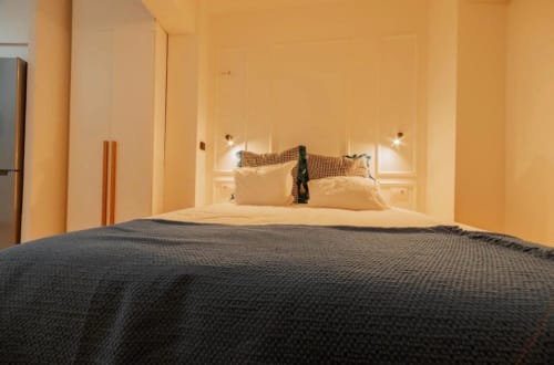 Dormitorio moderno del apartamento La Dormilona de Gestyp-AT en Mérida con cama oscura, almohadas color crema e iluminación cálida