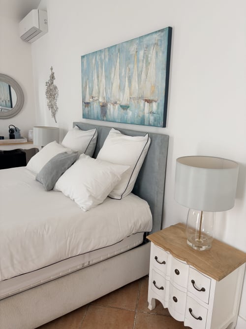 Das Schlafzimmer Sainte Maxime in La Parenthèse de Villepey mit grauem Polsterbett, weißer Bettwäsche, Segelbootkunstwerk und