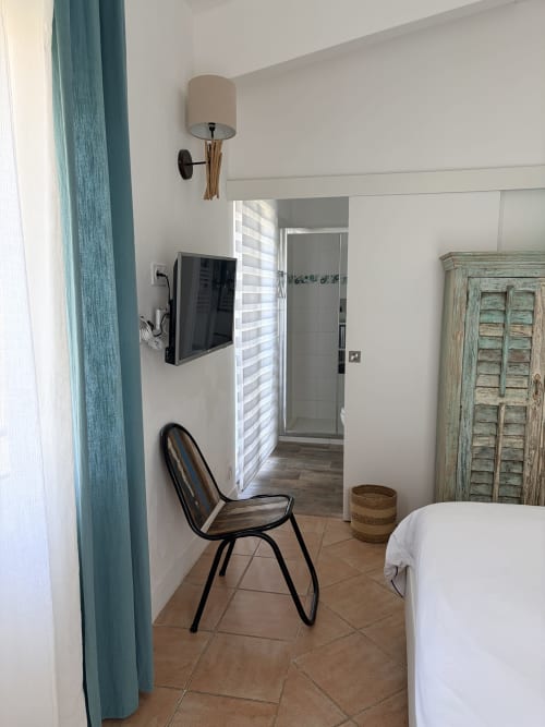 Modernes Hotelzimmer der La Parenthèse de Villepey mit Wandfernseher, Sessel und Badezimmereingang, Saint Aygulf