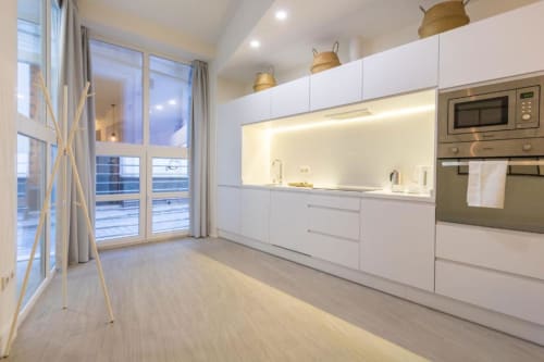 Moderna cocina blanca en el apartamento Almirante Hoyos de Calma Places Sevilla con electrodomésticos de acero inoxidable y vistas a la ciudad