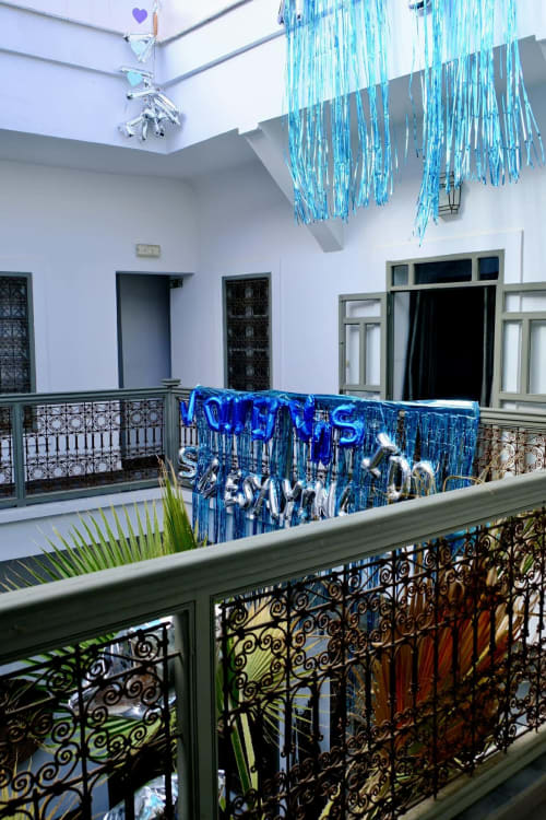 Riad 191 Marrakech courtyard with blue party decorations, ornate railings, and turquoise fringe ceiling