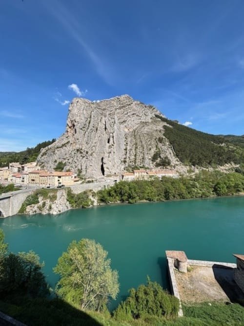 Falaise du Rocher de la Baume de Sisteron dominant la Durance turquoise avec les bâtiments historiques et les montagnes boisées