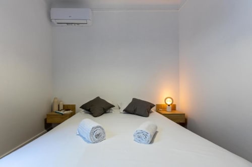 Quarto moderno em Aveiro com Paixão com roupa de cama branca, almofadas escuras, toalhas enroladas e iluminação acolhedora