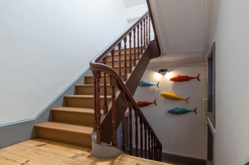 Escada de madeira com arte decorativa de peixes na parede do hall de entrada do apartamento em Aveiro
