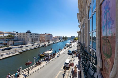 Vista do apartamento à beira-rio de Aveiro com canal, edifícios tradicionais e passeio ribeirinho em Portugal