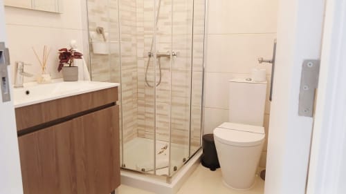Banheiro moderno do apartamento Sweet Home Amoreira em Portimão, com pia de madeira, box de vidro e vaso sanitário branco