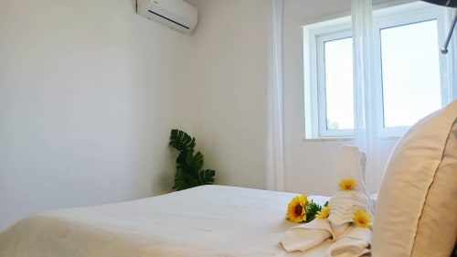Quarto iluminado no apartamento Sweet Home Amoreira em Portimão com cama branca, girassóis, planta monstera, ar condicionado e amplo
