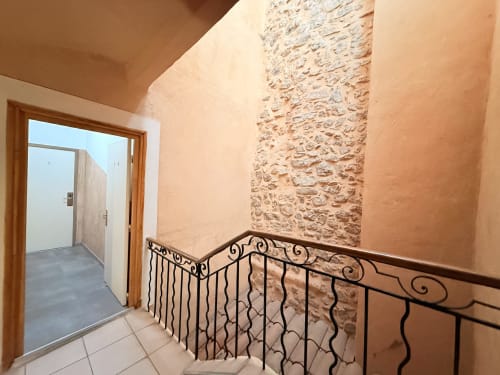 Palier d'escalier de l'hôtel Le Clos Androne à Sisteron avec rampe en fer forgé et murs en pierre texturée