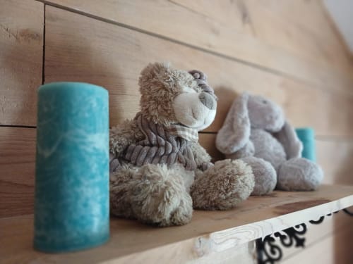 Cozy shelf display at Clos De La Gourmandiere B&B with stuffed animals and blue candle
