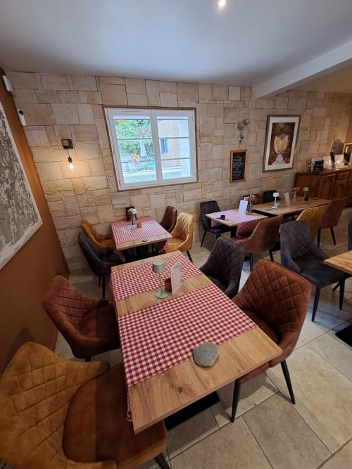 Dining area at Clos De La Gourmandiere B&B with wooden tables, red checkered cloths, and brown leather chairs