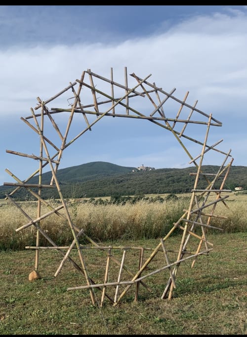 Arco rústico de madera con forma de estrella enmarcando la campiña toscana de Casale Artemisia, Capalbio