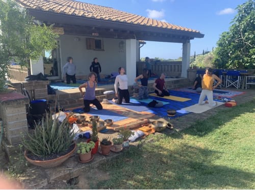 Clase de yoga al aire libre en Casale Artemisia B&B en Capalbio con huéspedes sobre colchonetas bajo pérgola