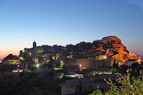 Casale Artemisia B&B a Capalbio illuminato al tramonto con edifici in pietra tradizionali e fortezza sulla collina