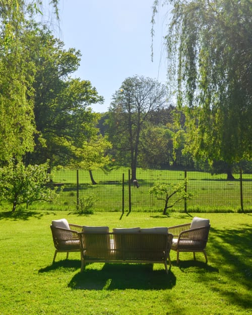 Outdoor seating area at Hôtel Des Vosges in Sommerau with wicker chairs on manicured lawn surrounded by trees