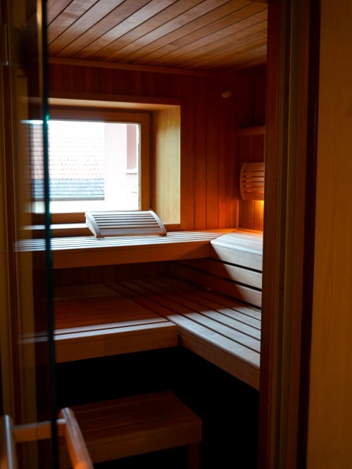 Traditionnel sauna en bois à l'Hôtel Des Vosges à Sommerau avec bancs et vue sur la fenêtre