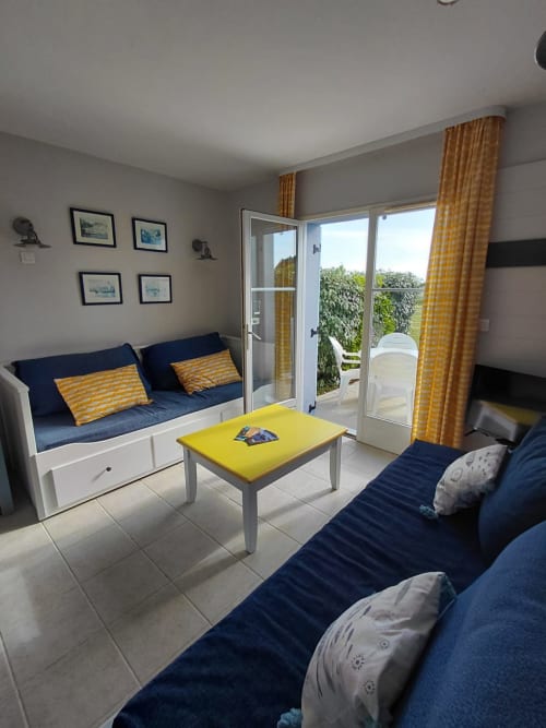 Séjour moderne avec canapés bleu marine, touches de jaune et portes-fenêtres vue mer à Loc'Maria Belle Île en Mer
