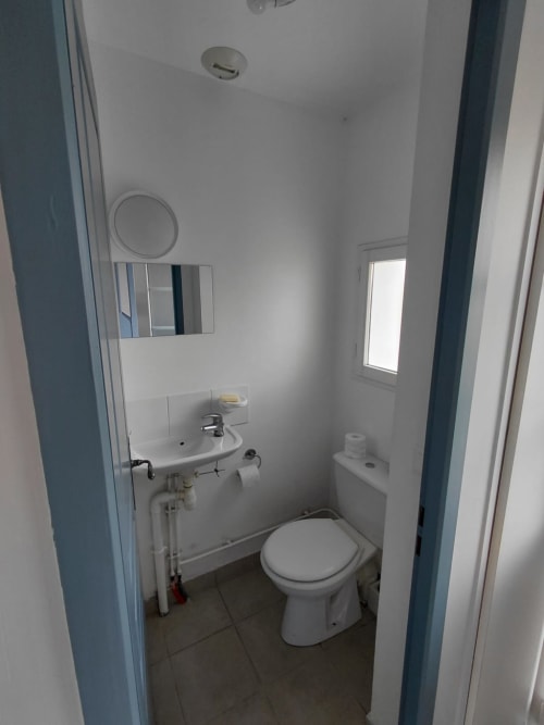 Petite salle de bain avec toilettes, lavabo et miroir à Locmaria, vue sur mer à Belle Île en Mer