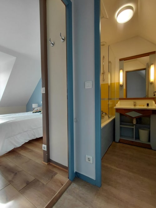Salle de bain moderne avec vanité et miroir dans un appartement de Belle Île en Mer, cloison bleue séparant la chambre