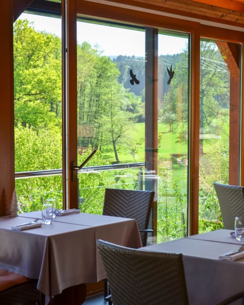 Salle à manger élégante de l'Hôtel Des Vosges avec baies vitrées panoramiques surplombant un paysage de vallée verdoyante à Sommerau