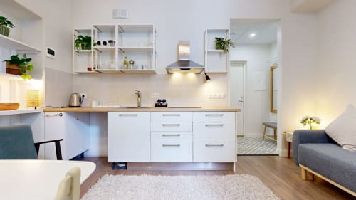 Modern studio apartment kitchen and living area at tARTu Stays in Tartu with white cabinetry, wooden countertop, and